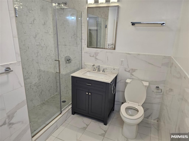 bathroom featuring vanity, toilet, a shower with door, and tile walls