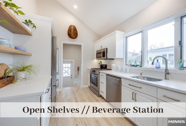 kitchen featuring white cabinets, sink, vaulted ceiling, a healthy amount of sunlight, and stainless steel appliances