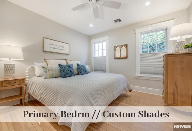 bedroom featuring ceiling fan, multiple windows, and light hardwood / wood-style flooring