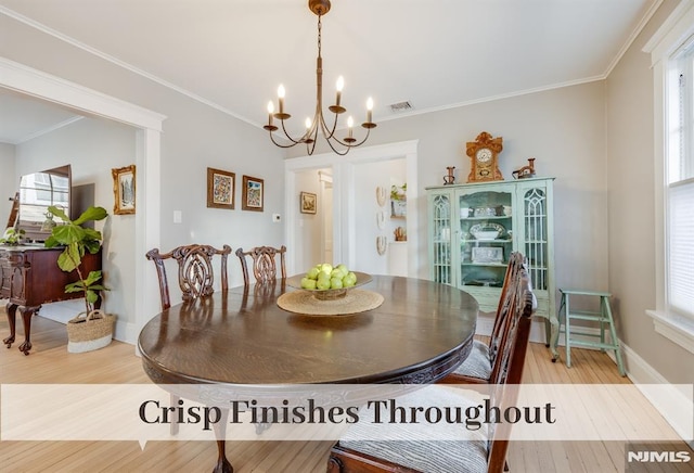 dining room with a notable chandelier, light wood-type flooring, and crown molding