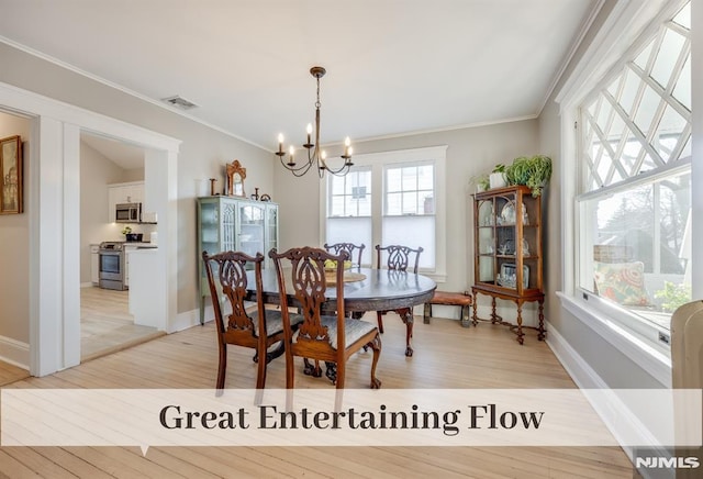 dining area featuring light wood-type flooring, an inviting chandelier, and ornamental molding