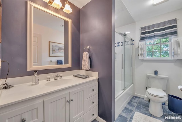 full bathroom featuring vanity, toilet, and bath / shower combo with glass door