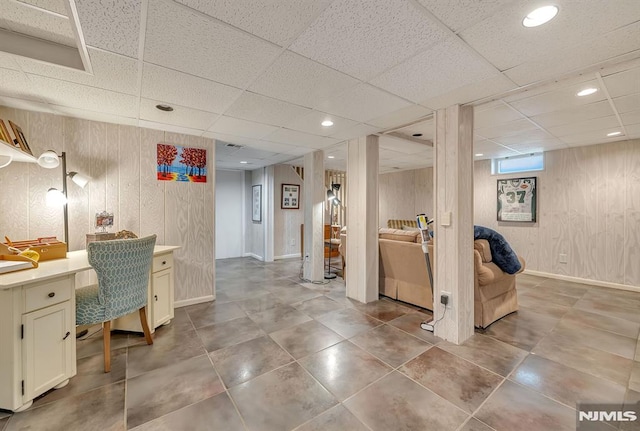 office space with built in desk, a paneled ceiling, and wooden walls