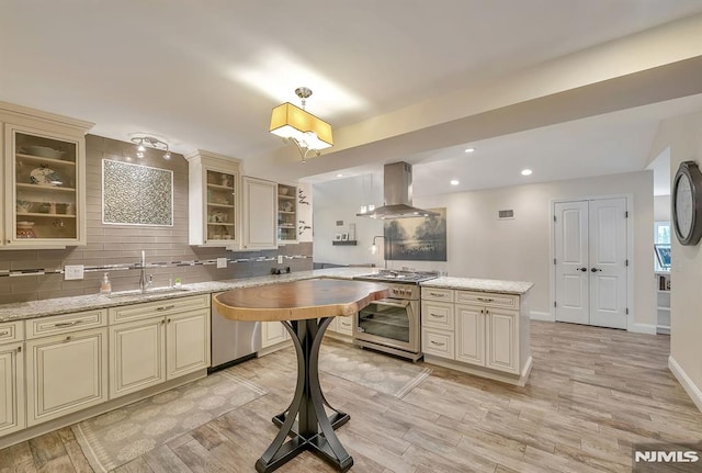 kitchen featuring light hardwood / wood-style flooring, dishwasher, cream cabinets, island exhaust hood, and light stone counters