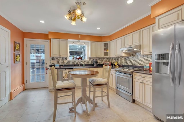 kitchen featuring cream cabinetry, baseboard heating, stainless steel appliances, and a wealth of natural light