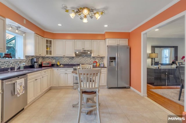 kitchen with appliances with stainless steel finishes, backsplash, crown molding, sink, and light tile patterned floors