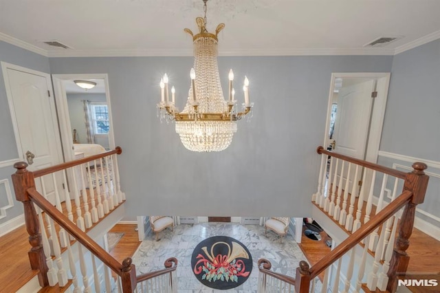 stairway featuring wood-type flooring, an inviting chandelier, and ornamental molding