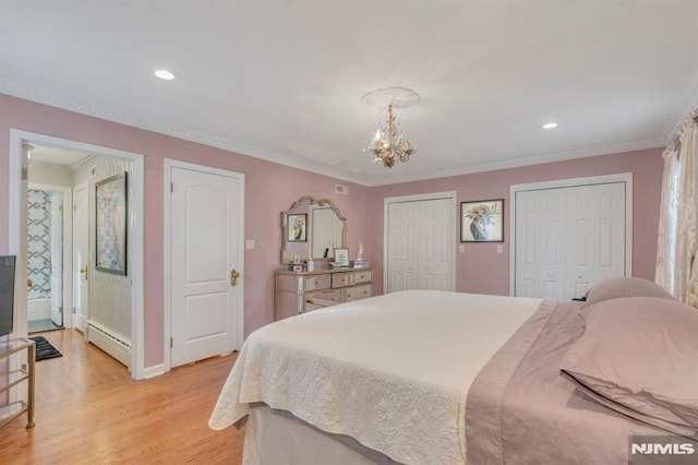 bedroom with ornamental molding, two closets, baseboard heating, a chandelier, and light hardwood / wood-style floors