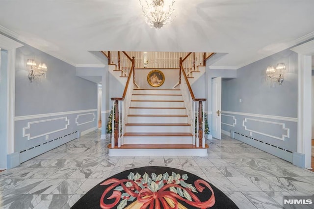 stairs with crown molding, a baseboard heating unit, and a notable chandelier