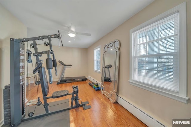 workout room featuring hardwood / wood-style flooring, baseboard heating, and ceiling fan