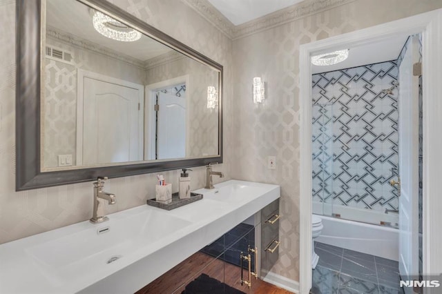 full bathroom with crown molding, sink, bath / shower combo with glass door, and toilet