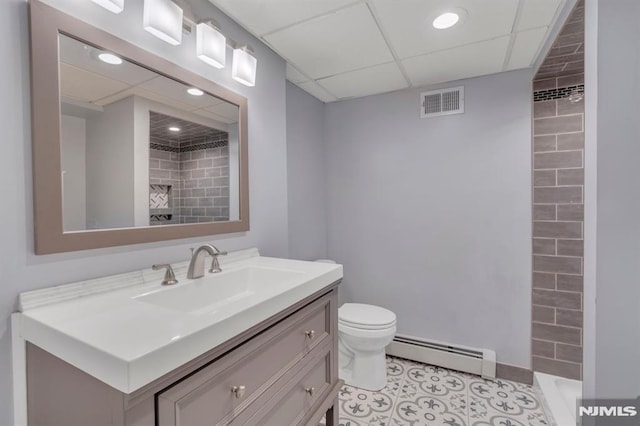 bathroom with vanity, toilet, a drop ceiling, and a baseboard heating unit