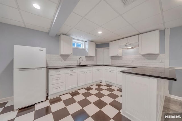 kitchen with white cabinets, white refrigerator, a drop ceiling, and sink