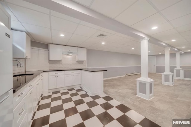 kitchen with sink, baseboard heating, backsplash, a paneled ceiling, and white cabinets