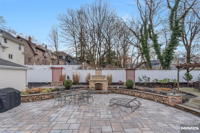 view of patio with an outdoor stone fireplace and grilling area