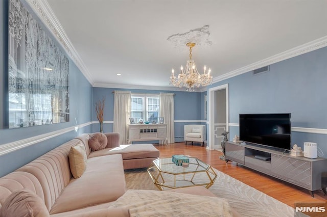 living room featuring light wood-type flooring, ornamental molding, baseboard heating, and a chandelier