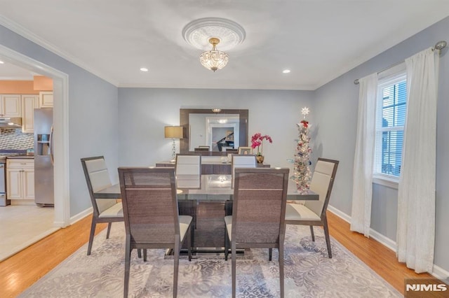 dining area featuring light wood-type flooring and crown molding