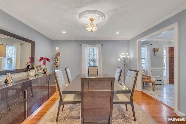 dining area with light hardwood / wood-style floors, ornamental molding, and a chandelier