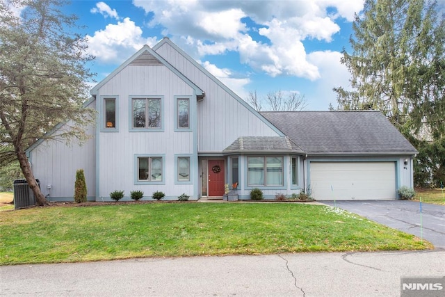 view of front of home featuring central AC, a front lawn, and a garage