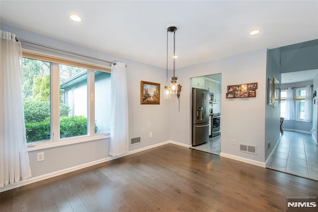 unfurnished dining area featuring dark wood-type flooring and an inviting chandelier