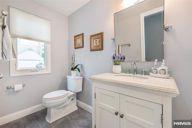 bathroom with toilet, hardwood / wood-style floors, and vanity