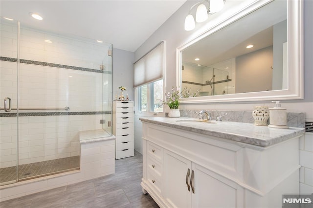 bathroom featuring tile patterned floors, a shower with shower door, and vanity