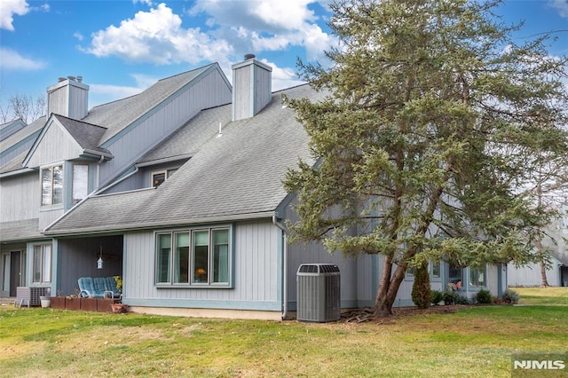 back of house with central air condition unit and a lawn