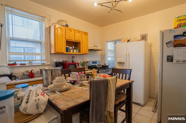 kitchen with light brown cabinets, a chandelier, stainless steel gas stove, white fridge, and white fridge with ice dispenser