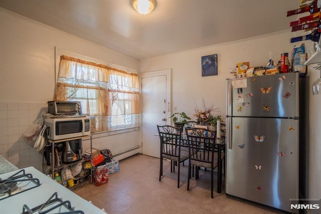 kitchen featuring baseboard heating, tile walls, and stainless steel refrigerator