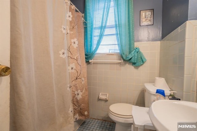 bathroom featuring tile patterned flooring, toilet, and tile walls