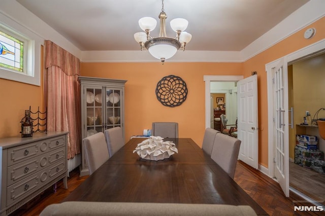 dining area with dark parquet flooring, french doors, and a chandelier