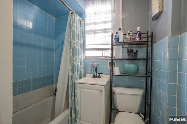 full bathroom with shower / bath combination with curtain, toilet, tile walls, and vanity