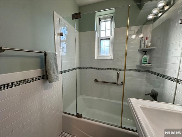 bathroom with shower / bath combination with glass door and tile walls