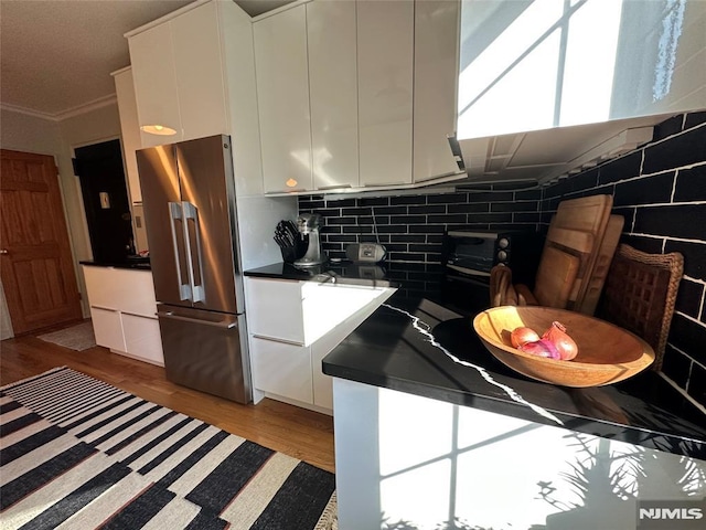 kitchen with white cabinets, backsplash, and high end fridge