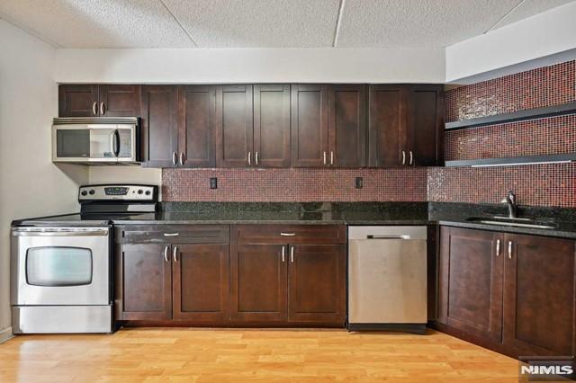 kitchen featuring decorative backsplash, light hardwood / wood-style floors, sink, and appliances with stainless steel finishes