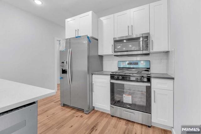 kitchen with white cabinets, stainless steel appliances, and light hardwood / wood-style floors