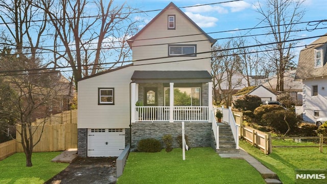 view of front of house with covered porch, a front yard, and a garage