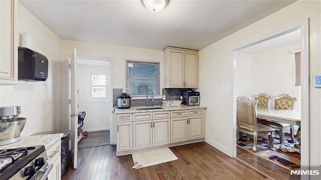 kitchen featuring light stone countertops, sink, tasteful backsplash, dark hardwood / wood-style floors, and cream cabinetry