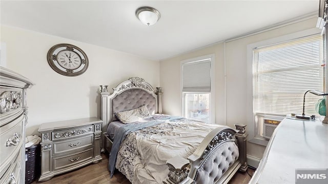 bedroom with dark hardwood / wood-style floors, cooling unit, multiple windows, and a baseboard radiator