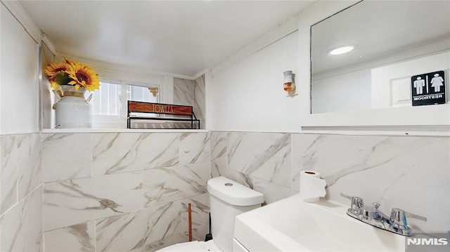 bathroom featuring sink, tile walls, and toilet