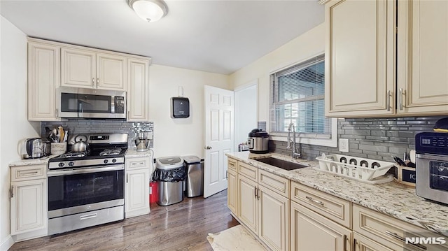 kitchen with tasteful backsplash, cream cabinets, stainless steel appliances, and sink