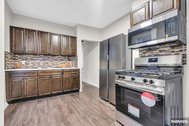 kitchen featuring dark brown cabinetry, backsplash, stainless steel appliances, and hardwood / wood-style flooring