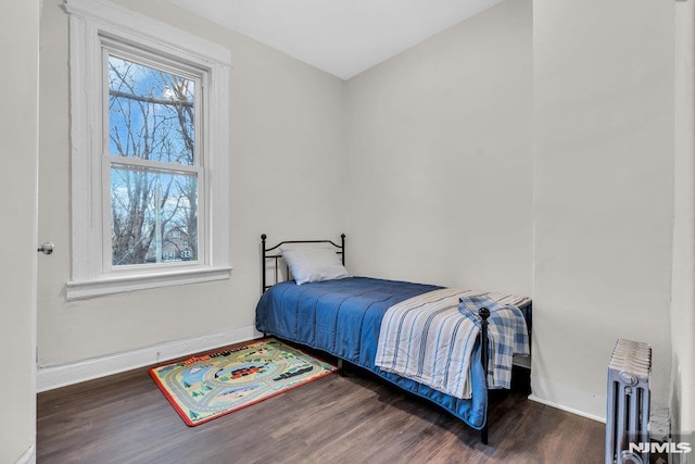 bedroom featuring multiple windows, radiator heating unit, and dark wood-type flooring