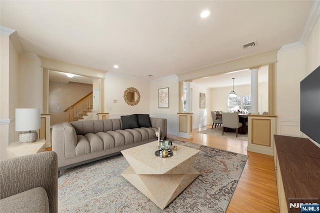 living room featuring ornamental molding, light hardwood / wood-style floors, and ornate columns