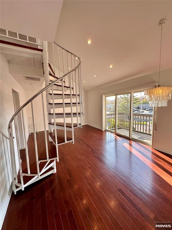 unfurnished living room with a chandelier and dark hardwood / wood-style floors