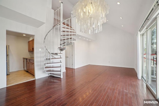 unfurnished living room featuring an inviting chandelier, hardwood / wood-style floors, and high vaulted ceiling