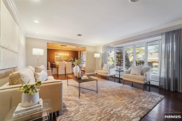 living room with a chandelier, hardwood / wood-style floors, baseboard heating, and ornamental molding