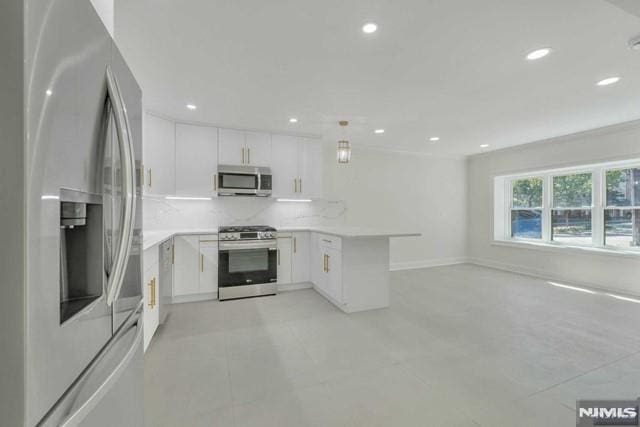 kitchen featuring kitchen peninsula, appliances with stainless steel finishes, decorative backsplash, ornamental molding, and white cabinets