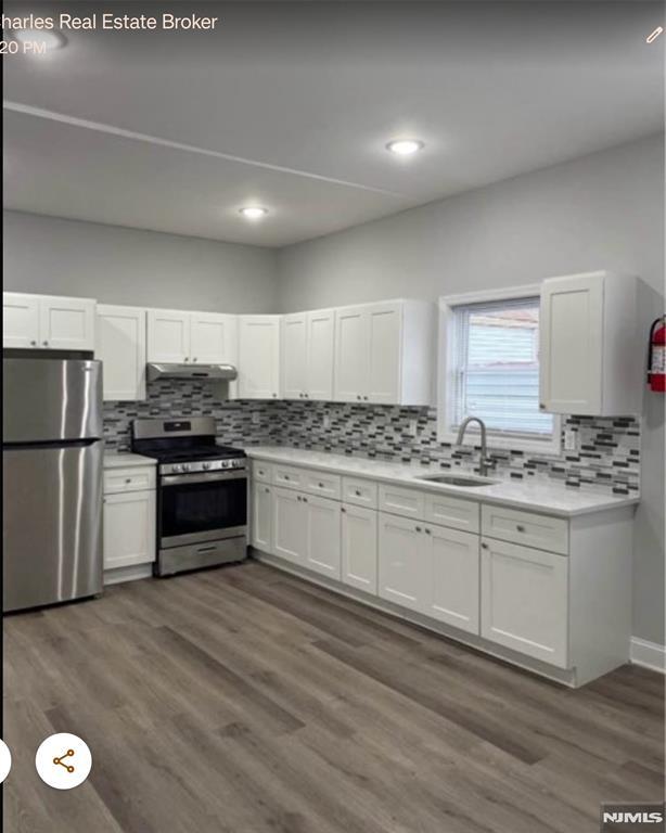 kitchen with white cabinets, appliances with stainless steel finishes, dark hardwood / wood-style floors, and sink