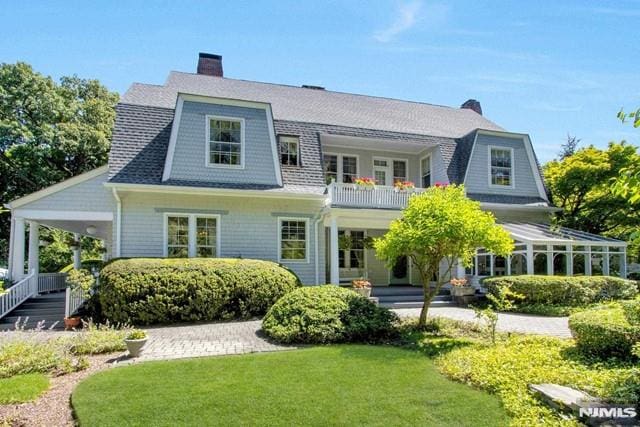 back of property featuring a lawn, a porch, and a balcony